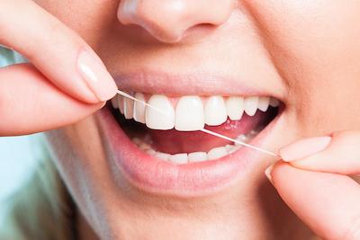 Close up of person flossing with veneers in Fredericksburg, VA